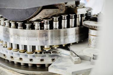 Background shot of punch tools in tablet press machine compressing powder into pills at pharmaceutical manufacturing plant