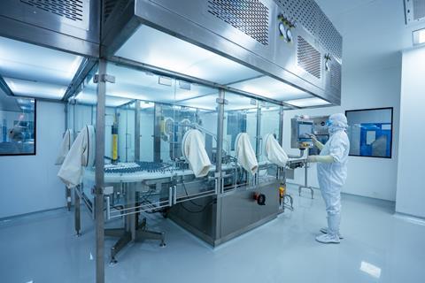 pharmaceutical worker checking operating large machine. medicine making factory. person wearing a ppe kit in a factory